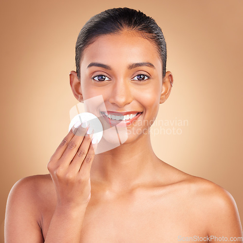 Image of Smile, skincare and cotton with portrait of indian woman in studio for self care, makeup remover and cosmetics. Beauty, clean and glow with model on brown background for results, natural and facial