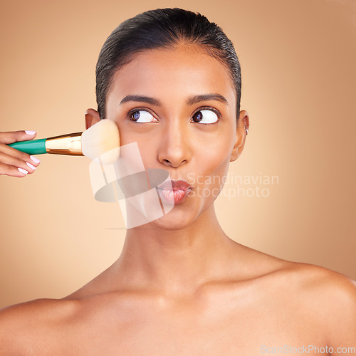 Image of Makeup, beauty and brush with indian woman in studio for foundation, blush and self care. Glow, cosmetics and facial with female model isolated on brown background for shine, clean and confidence