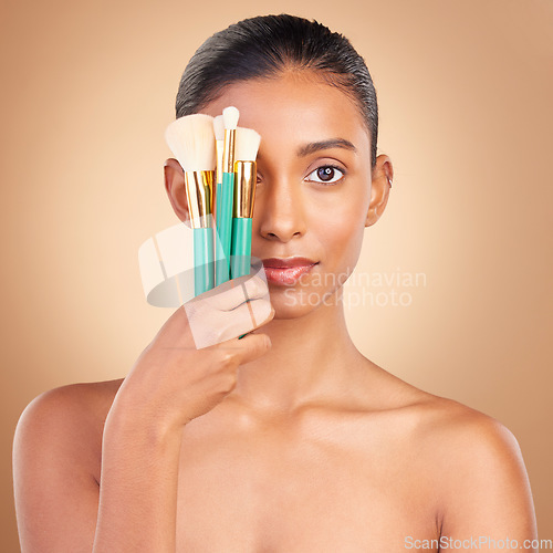 Image of Makeup, cover and brush with portrait of Indian woman in studio for foundation, blush and self care. Glow, cosmetics and facial with female model on brown background for shine, clean and confidence