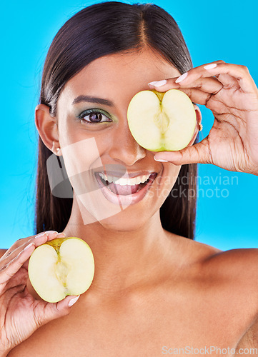 Image of Skincare, smile and portrait of Indian woman with apple slices and facial detox with fruit on blue background. Health, wellness and face of model with organic luxurycleaning and grooming cosmetics.