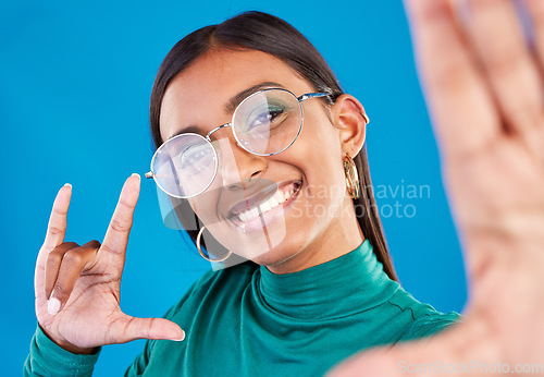 Image of Woman, fashion and selfie portrait with rock on hand for gen z attitude on blue background with glasses. Face of happy model person in studio with smile or cool sign emoji for beauty and motivation