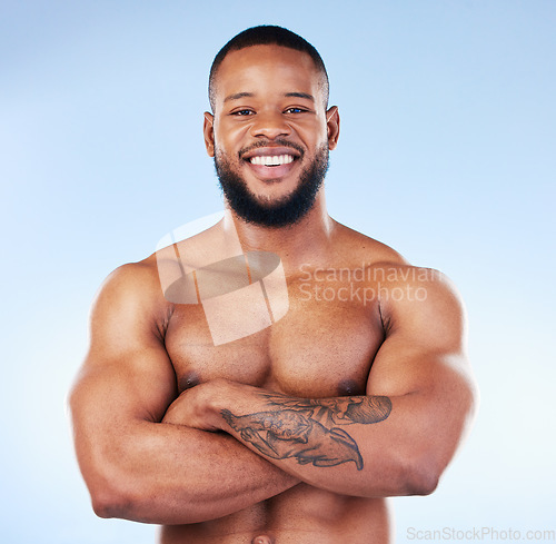 Image of Muscle, fit and portrait of a black man with arms crossed isolated on a blue background in studio. Happy, pride and African bodybuilder with fitness confidence, arm power and strength on a backdrop