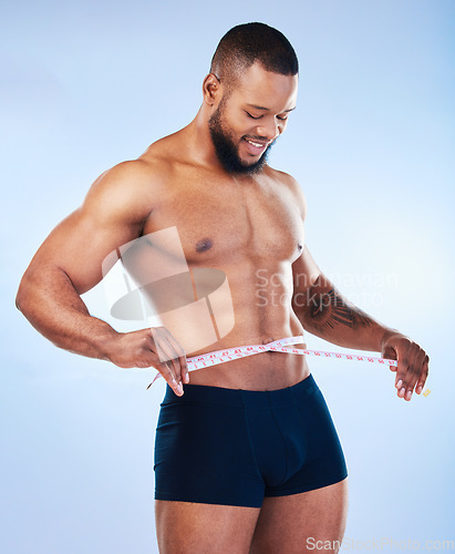 Image of Black man, fitness and body, weightloss and measuring tape with abs, health and active on blue background. Shirtless male bodybuilder, smile and exercise with diet, healthy and strong in underwear