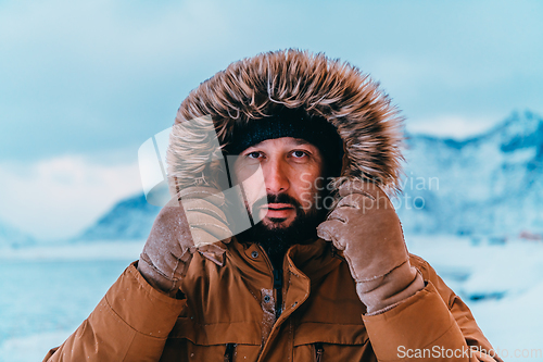 Image of Headshot photo of a man in a cold snowy area wearing a thick brown winter jacket and gloves. Life in cold regions of the country.