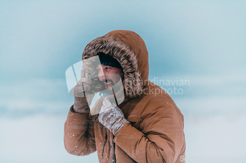 Image of Headshot photo of a man in a cold snowy area wearing a thick brown winter jacket and gloves. Life in cold regions of the country.