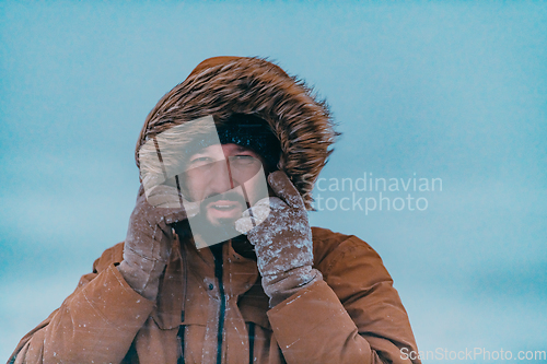 Image of Headshot photo of a man in a cold snowy area wearing a thick brown winter jacket and gloves. Life in cold regions of the country.