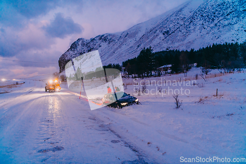 Image of The roadside assistance service pulling the car out of the canal. An incident on a frozen Scandinavian road.