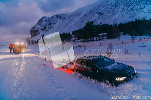 Image of The roadside assistance service pulling the car out of the canal. An incident on a frozen Scandinavian road.