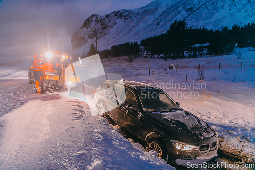 Image of The roadside assistance service pulling the car out of the canal. An incident on a frozen Scandinavian road.