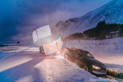 Image of The roadside assistance service pulling the car out of the canal. An incident on a frozen Scandinavian road.