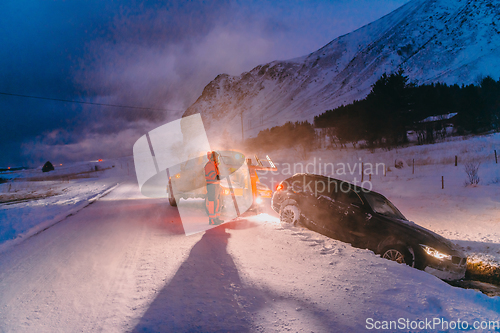 Image of The roadside assistance service pulling the car out of the canal. An incident on a frozen Scandinavian road.