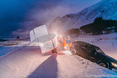 Image of The roadside assistance service pulling the car out of the canal. An incident on a frozen Scandinavian road.