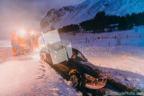 Image of The roadside assistance service pulling the car out of the canal. An incident on a frozen Scandinavian road.