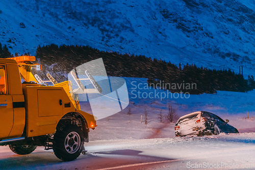 Image of The roadside assistance service pulling the car out of the canal. An incident on a frozen Scandinavian road.