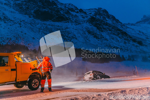 Image of The roadside assistance service pulling the car out of the canal. An incident on a frozen Scandinavian road.