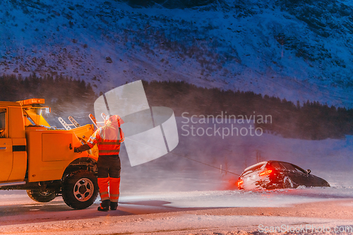 Image of The roadside assistance service pulling the car out of the canal. An incident on a frozen Scandinavian road.