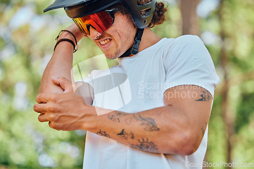 Image of Sport, injury and man with arm pain, problem or issue while cycling in a forest on blurred background. Injured, elbow and male cyclist suffering inflammation, arthritis or joint ache during exercise