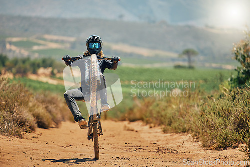 Image of Cycling, fitness and person on a bicycle in the countryside for extreme sport, adrenaline and fun. Speed, action and cyclist on a dirt road for stunt, trick or training, freedom and balance in nature