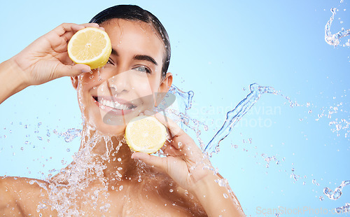 Image of Beauty, lemon and water splash with portrait of woman in studio for natural cosmetics, nutrition and detox. Glow, fruits and hydration with female on blue background for diet, clean face and skincare