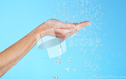 Image of Hands, cleaning and water in a studio for skincare, safety and healthcare from virus. Isolated, blue background and hand wash for hygiene wellness and sanitary protection with liquid stream to clean