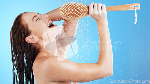 Image of Shower karaoke, skincare and woman with happiness singing in a studio. Bathroom, music and happy female model with isolated blue background and cleaning brush for beauty routine and wellness