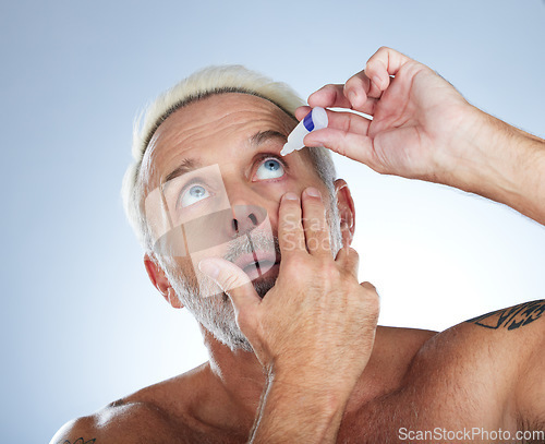 Image of Eye drops, senior man and studio with medical, healthcare and wellness pharmaceuticals. Isolated, blue background and male model with dry eyes and medicine for vision solution and allergy product