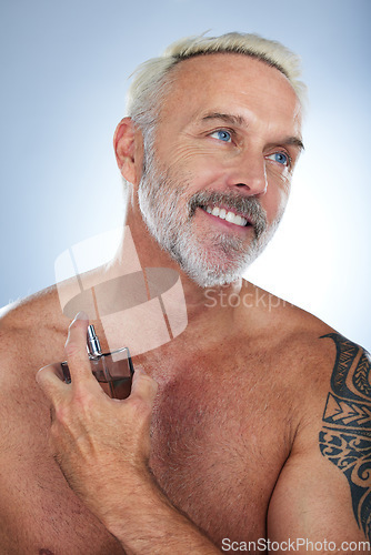 Image of Senior man, cologne bottle and smile in a studio with a male model and perfume spray. Happy, skincare and elderly person doing dermatology, beauty and body care smell routine with grey background