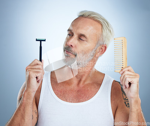 Image of Senior man, shaver and comb thinking for grooming, skincare or hair removal against studio background. thoughtful mature male holding razor blade and brush for haircare, cosmetics or facial treatment