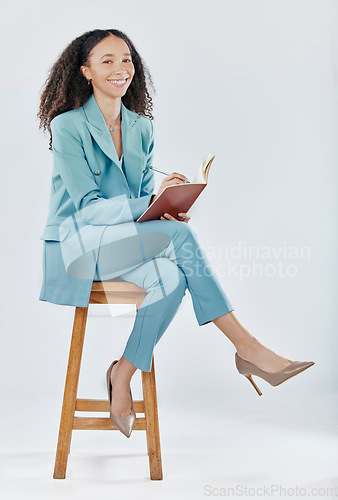 Image of Planning, happy and a woman writing in a notebook isolated on a white background in a studio. Smile, creative and a girl in business sitting with a book for an agenda, ideas and notes on a backdrop