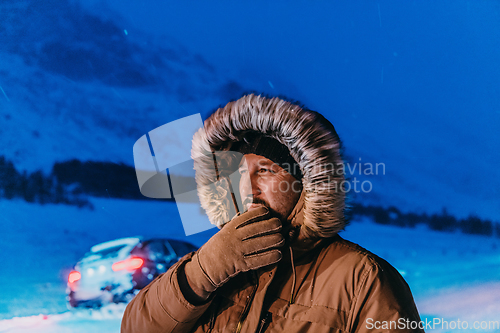 Image of Head shot of a man in a cold snowy area wearing a thick brown winter jacket, snow goggles and gloves on a cold Scandinavian night. Life in the cold regions of the country.