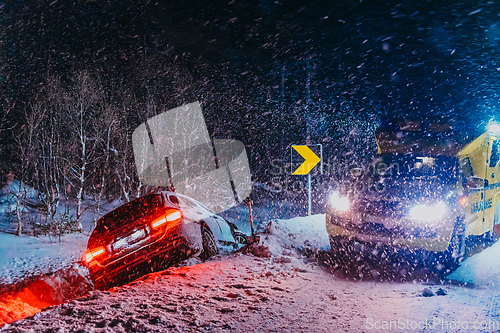 Image of The roadside assistance service pulling the car out of the canal. An incident on a frozen Scandinavian road.