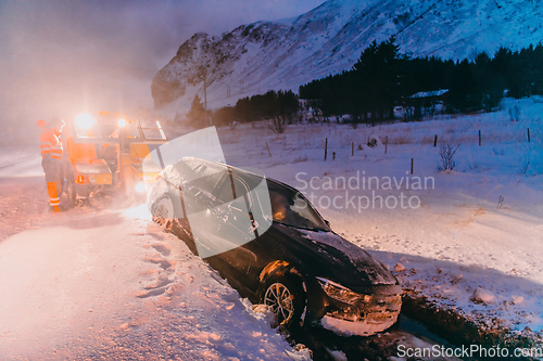 Image of The roadside assistance service pulling the car out of the canal. An incident on a frozen Scandinavian road.