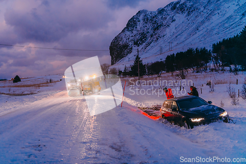 Image of The roadside assistance service pulling the car out of the canal. An incident on a frozen Scandinavian road.