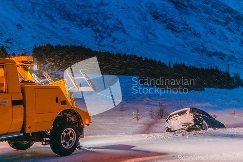 Image of The roadside assistance service pulling the car out of the canal. An incident on a frozen Scandinavian road.