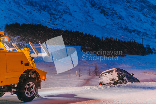 Image of The roadside assistance service pulling the car out of the canal. An incident on a frozen Scandinavian road.