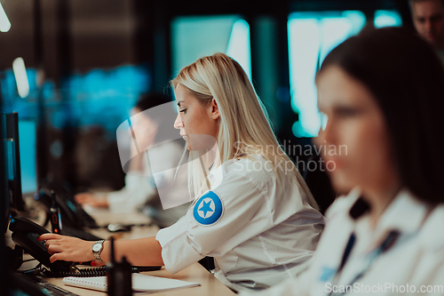 Image of Group of Security data center operators working in a CCTV monitoring room looking on multiple monitors.Officers Monitoring Multiple Screens for Suspicious Activities