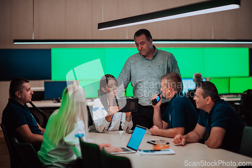 Image of Group of security guards sitting and having briefing In the system control room They're working in security data center surrounded by multiple Screens