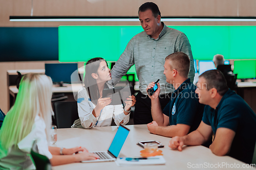 Image of Group of security guards sitting and having briefing In the system control room They're working in security data center surrounded by multiple Screens