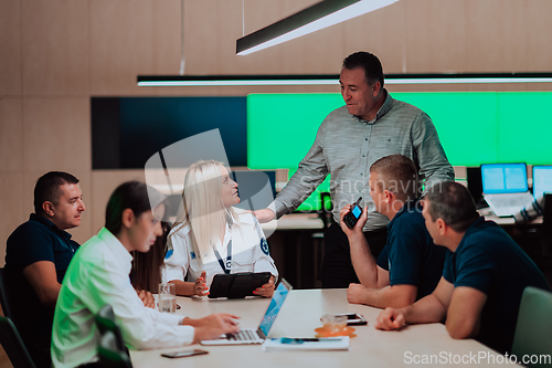 Image of Group of security guards sitting and having briefing In the system control room They're working in security data center surrounded by multiple Screens