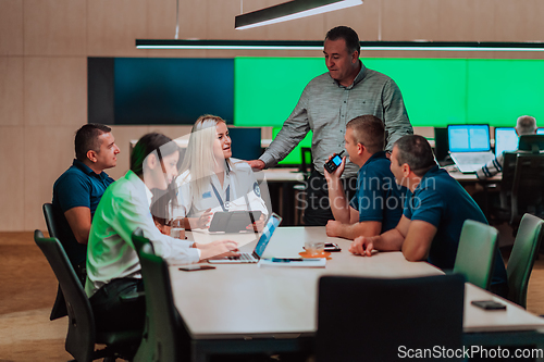 Image of Group of security guards sitting and having briefing In the system control room They're working in security data center surrounded by multiple Screens