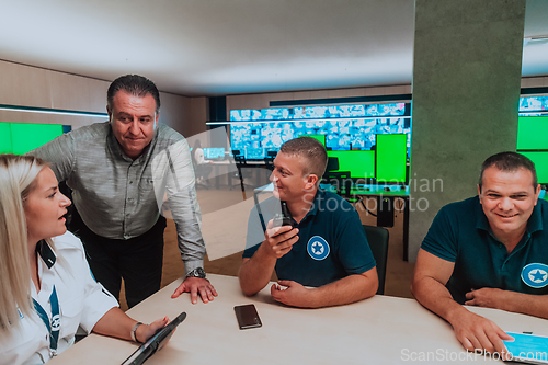 Image of Group of security guards sitting and having briefing In the system control room They're working in security data center surrounded by multiple Screens