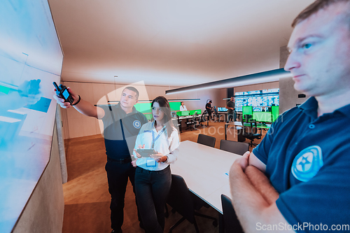 Image of Group of security operators working in a data system control room Technical Operators Working at workstation with multiple displays, security guards working on multiple monitors in surveillan