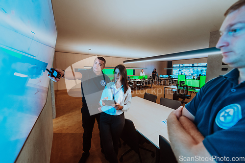 Image of Group of security operators working in a data system control room Technical Operators Working at workstation with multiple displays, security guards working on multiple monitors in surveillan