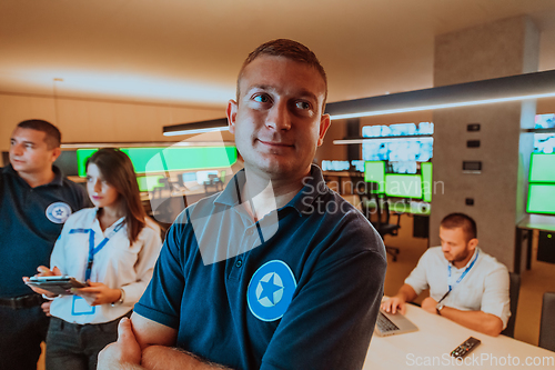 Image of Group of security operators working in a data system control room Technical Operators Working at workstation with multiple displays, security guards working on multiple monitors in surveillan