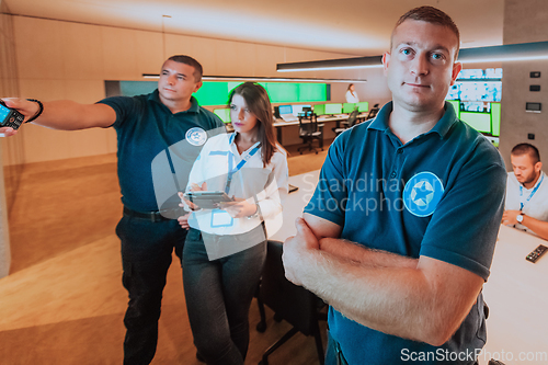 Image of Group of security operators working in a data system control room Technical Operators Working at workstation with multiple displays, security guards working on multiple monitors in surveillan