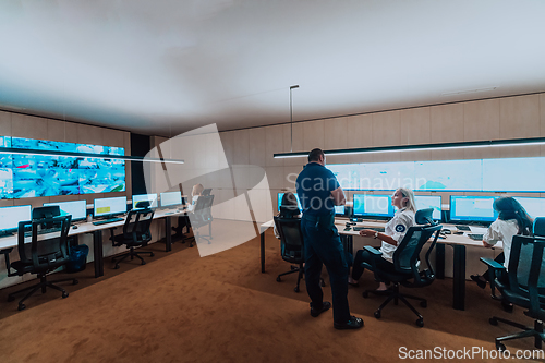 Image of Group of security operators working in a data system control room Technical Operators Working at workstation with multiple displays, security guards working on multiple monitors in surveillan