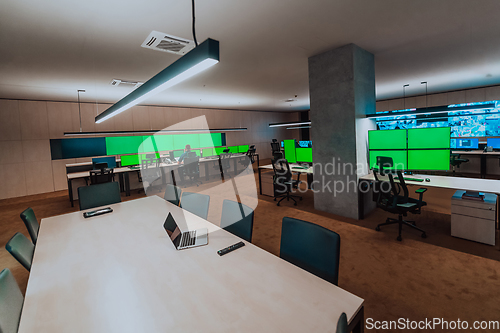 Image of Group of Security data center operators working in a CCTV monitoring room looking on multiple monitors.Officers Monitoring Multiple Screens for Suspicious Activities