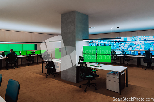 Image of Group of Security data center operators working in a CCTV monitoring room looking on multiple monitors.Officers Monitoring Multiple Screens for Suspicious Activities