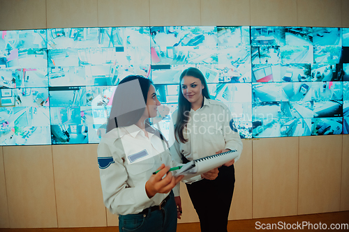 Image of Group portrait of female security operator while working in a data system control room offices Technical Operator Working at workstation with multiple displays