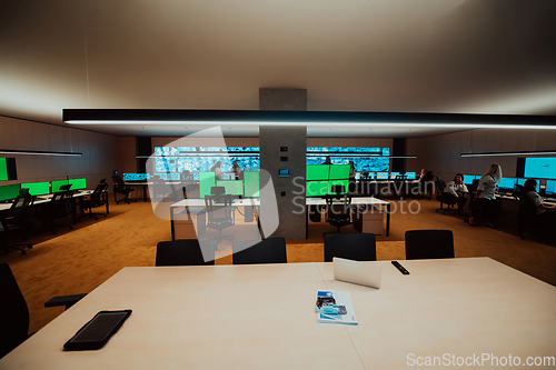 Image of Group of Security data center operators working in a CCTV monitoring room looking on multiple monitors.Officers Monitoring Multiple Screens for Suspicious Activities